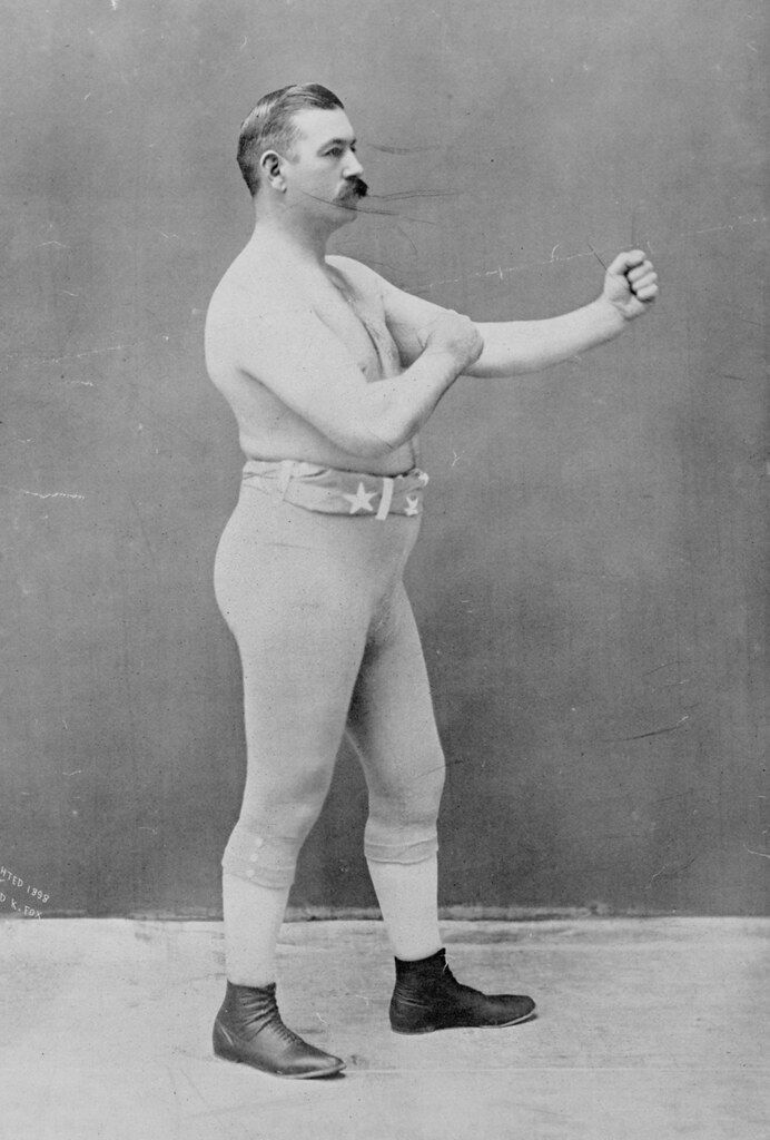 Vintage black and white photograph of a muscular man posing as a boxer.