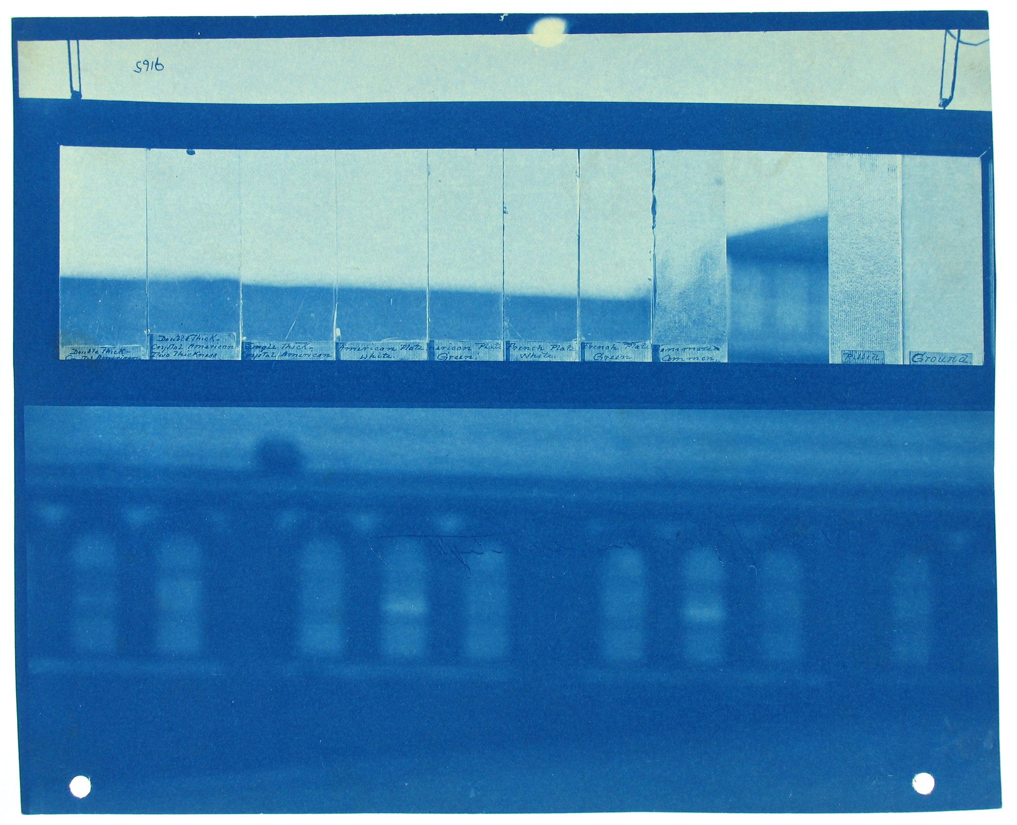 A cyanotype photograph with a grid-like pattern of blue and white sections, with handwritten labels above and mounted on cardboard.