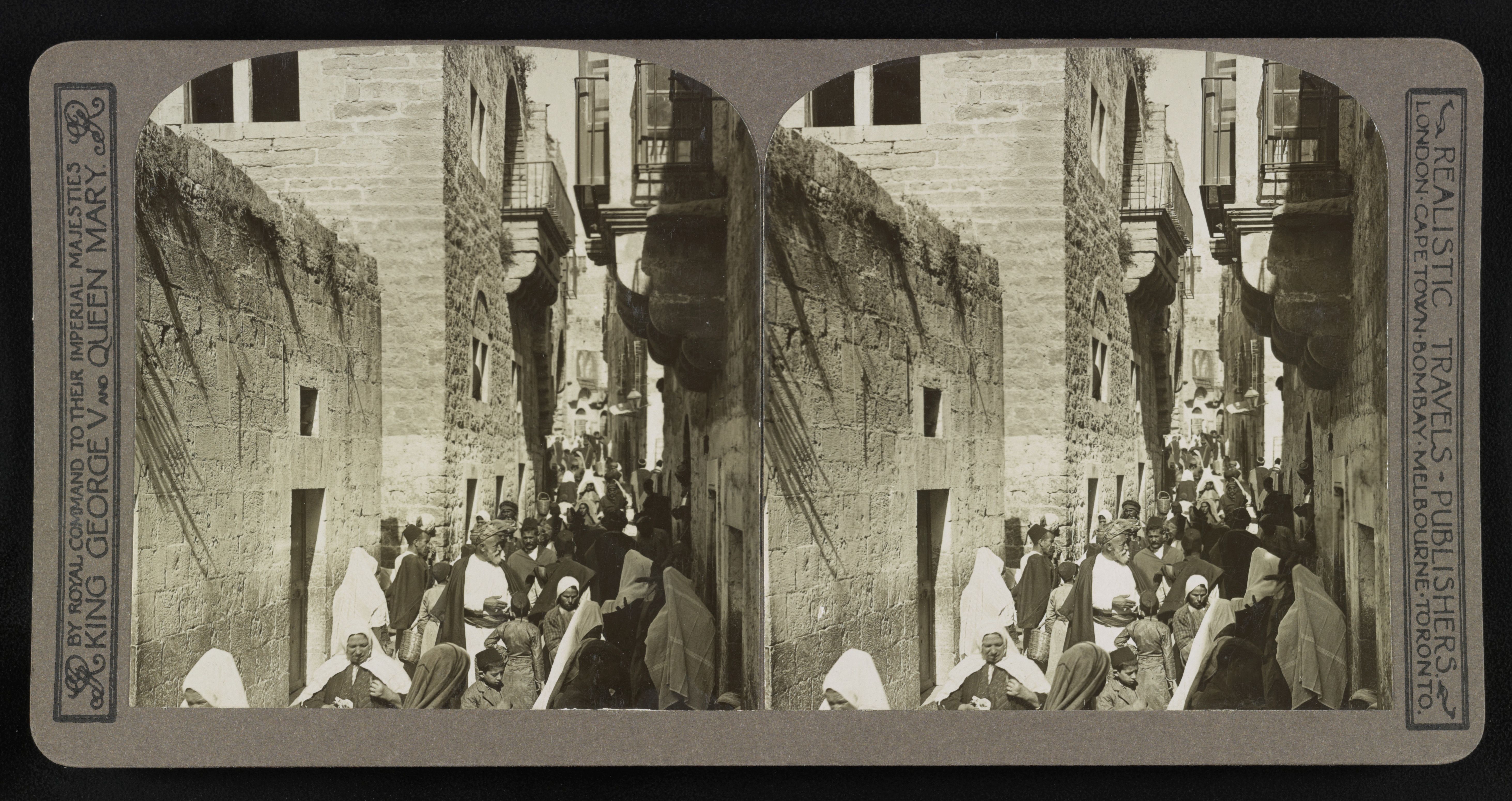 Stereoscopic photograph of a grand gateway with people standing in front, framed by a decorative border with publisher's text.