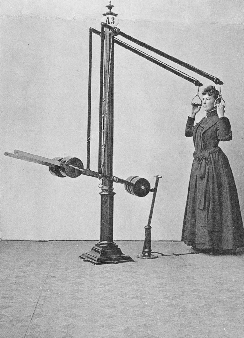 A vintage photograph of a woman wearing a headgear connected to a complex medical machine.