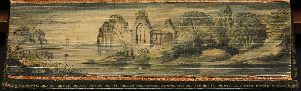 A long, rectangular textile with an embroidered landscape scene featuring mountains, trees, and water. The edges of the textile are adorned with a decorative border.