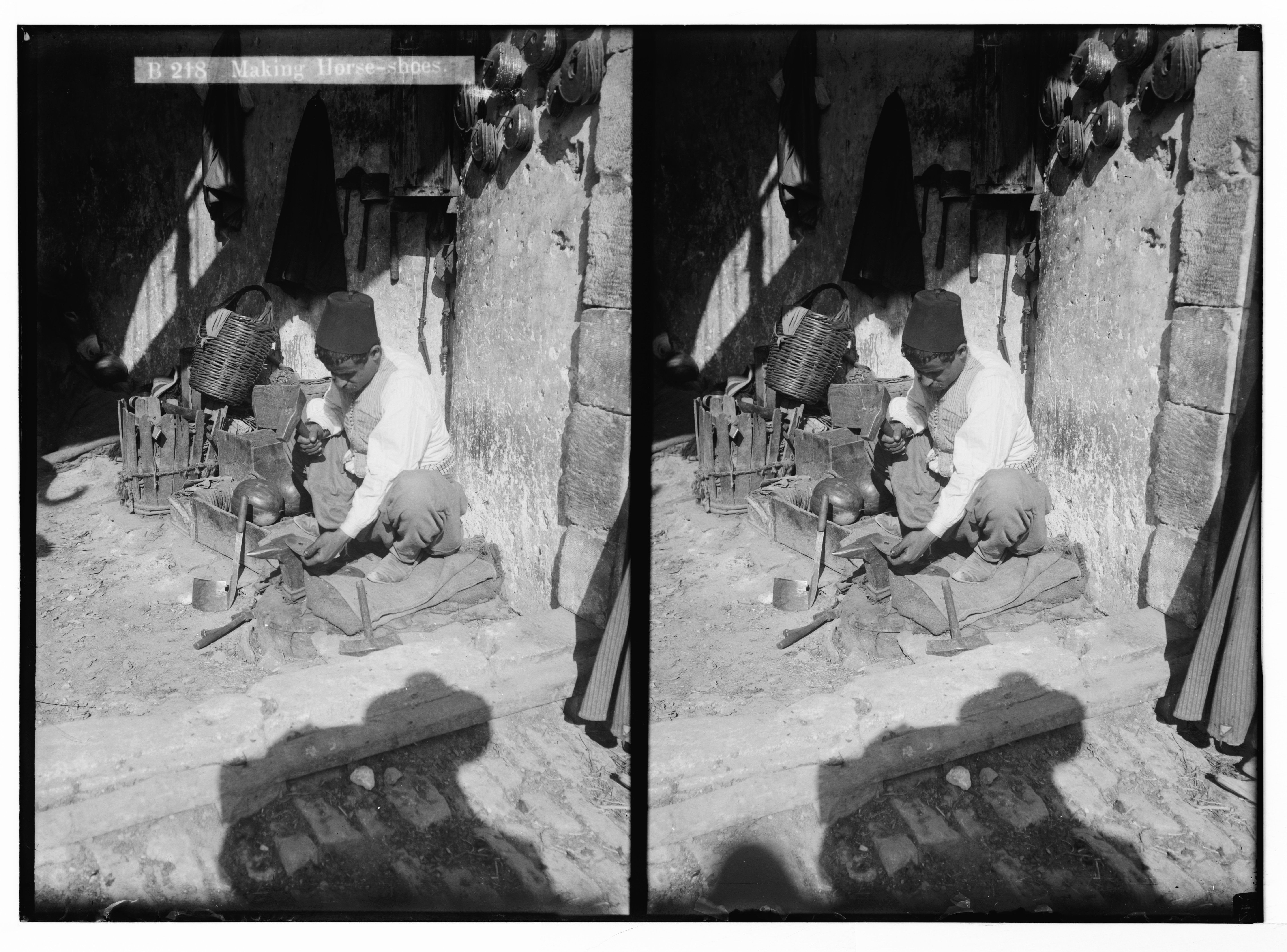Stereoscopic photograph of a blacksmith making horseshoes in an outdoor setting.