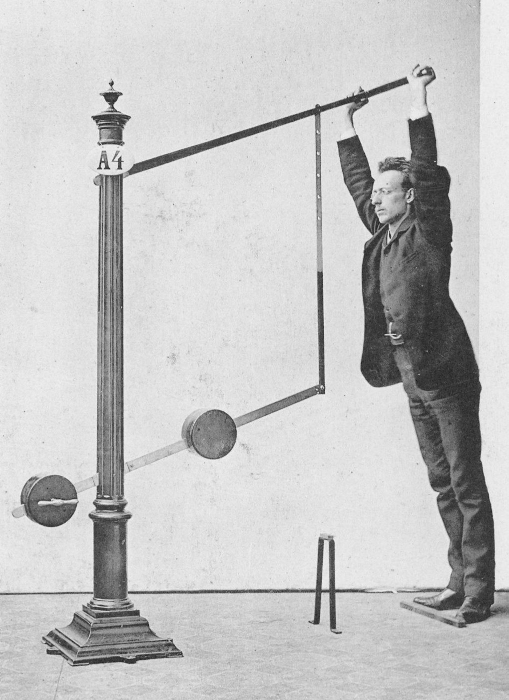 Vintage black and white photograph of a man using a mechanical lever system.