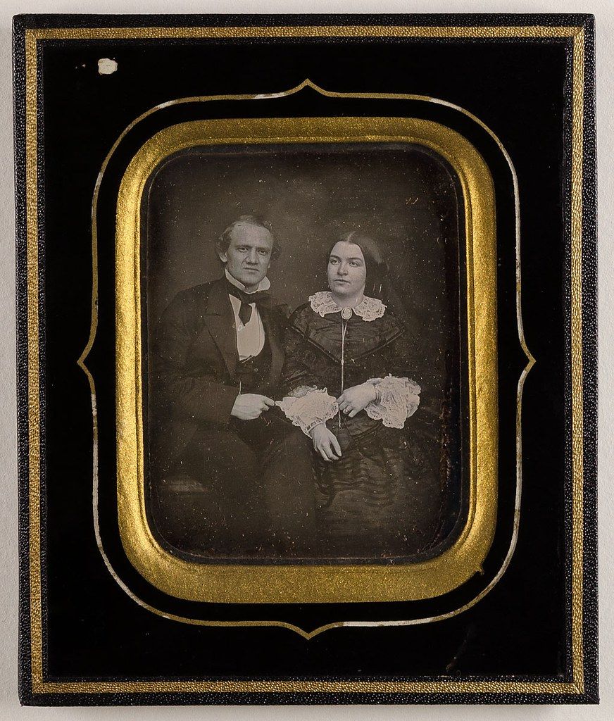 A daguerreotype portrait of a man and a woman in formal attire, encased in a decorative frame.