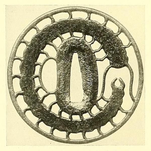 A vintage, circular tsuba with a coiled serpent design and openwork border.