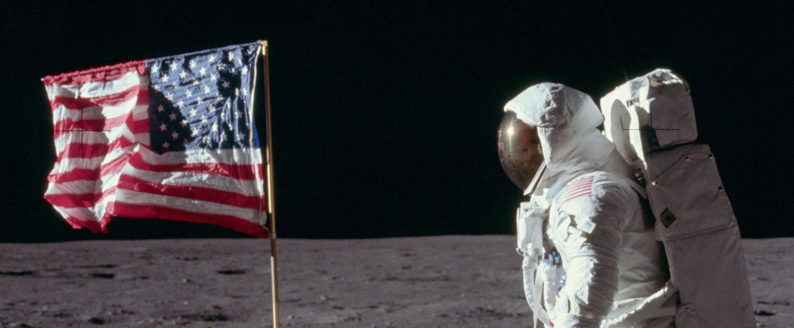 Astronaut standing near the American flag on the moon.
