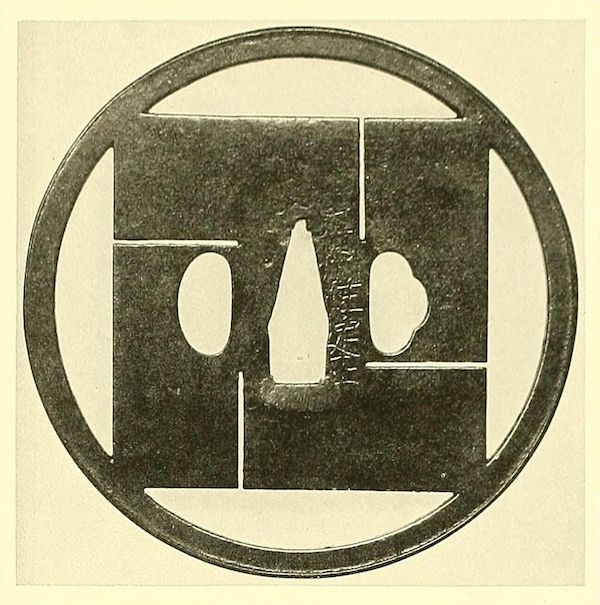 Close-up of a dark metal tsuba with an openwork design resembling a steering wheel and a central cutout of a Japanese bottle.