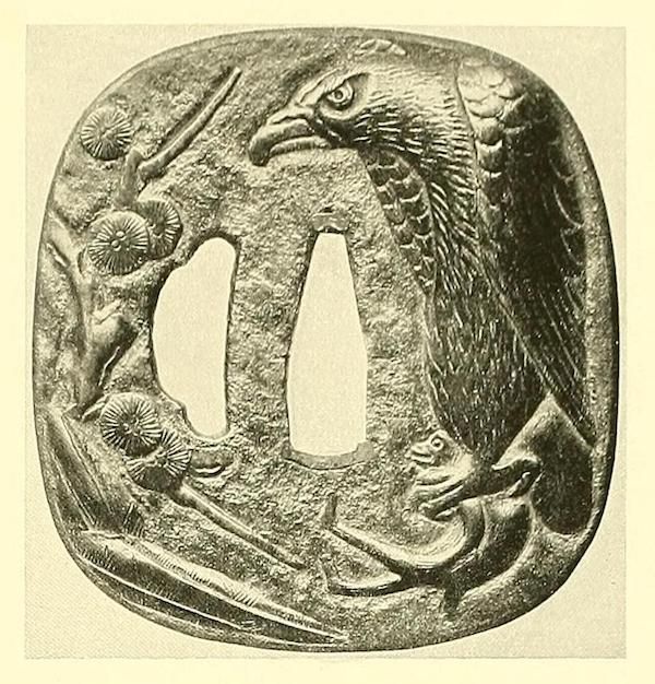 A detailed relief carving of a bird and flowers on a Japanese tsuba.
