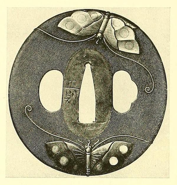 A detailed, circular tsuba (a Japanese sword guard) with two butterflies and a textured background.