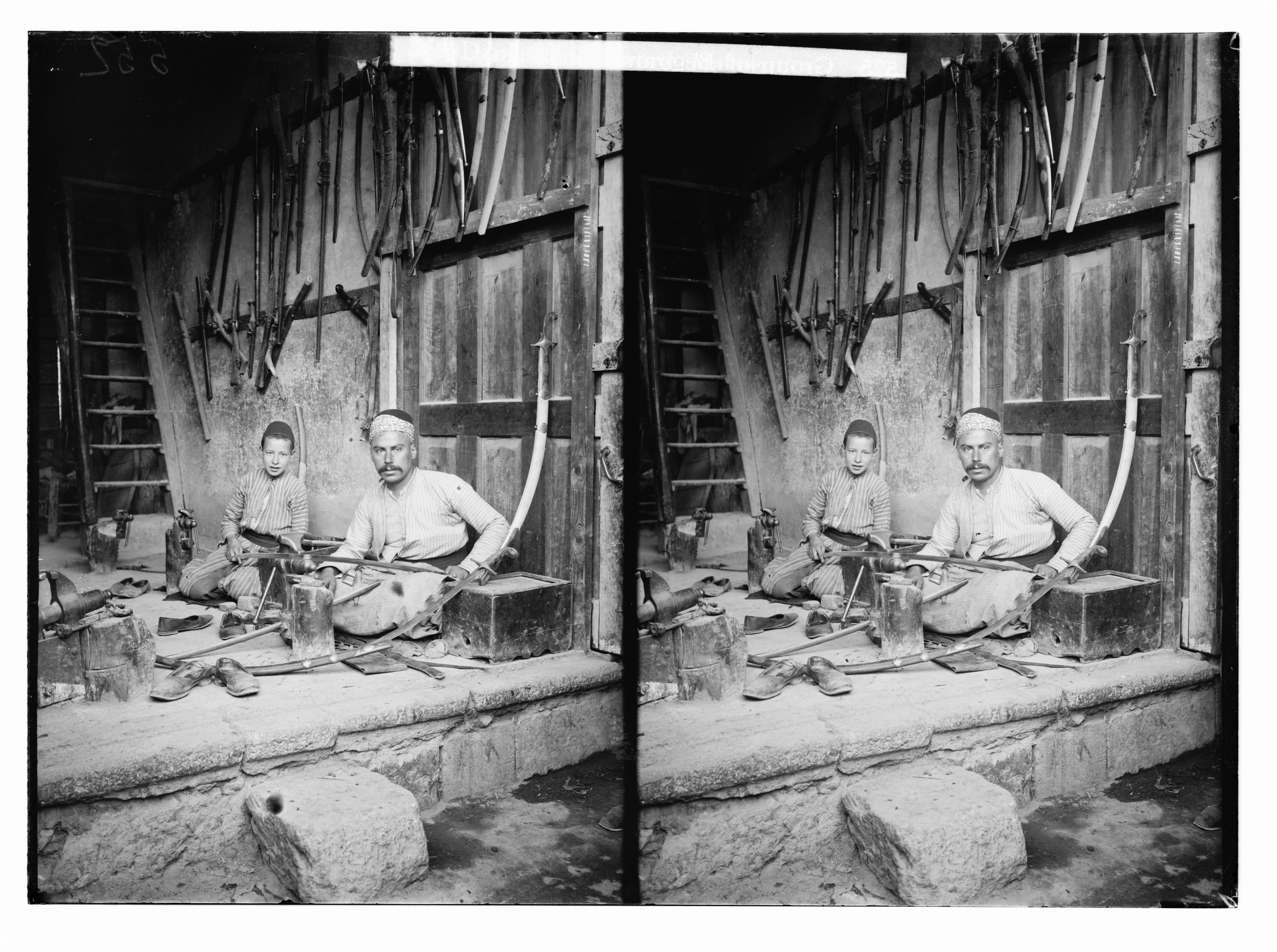 Stereoscopic photograph of two men working in a workshop, surrounded by tools and weapons.