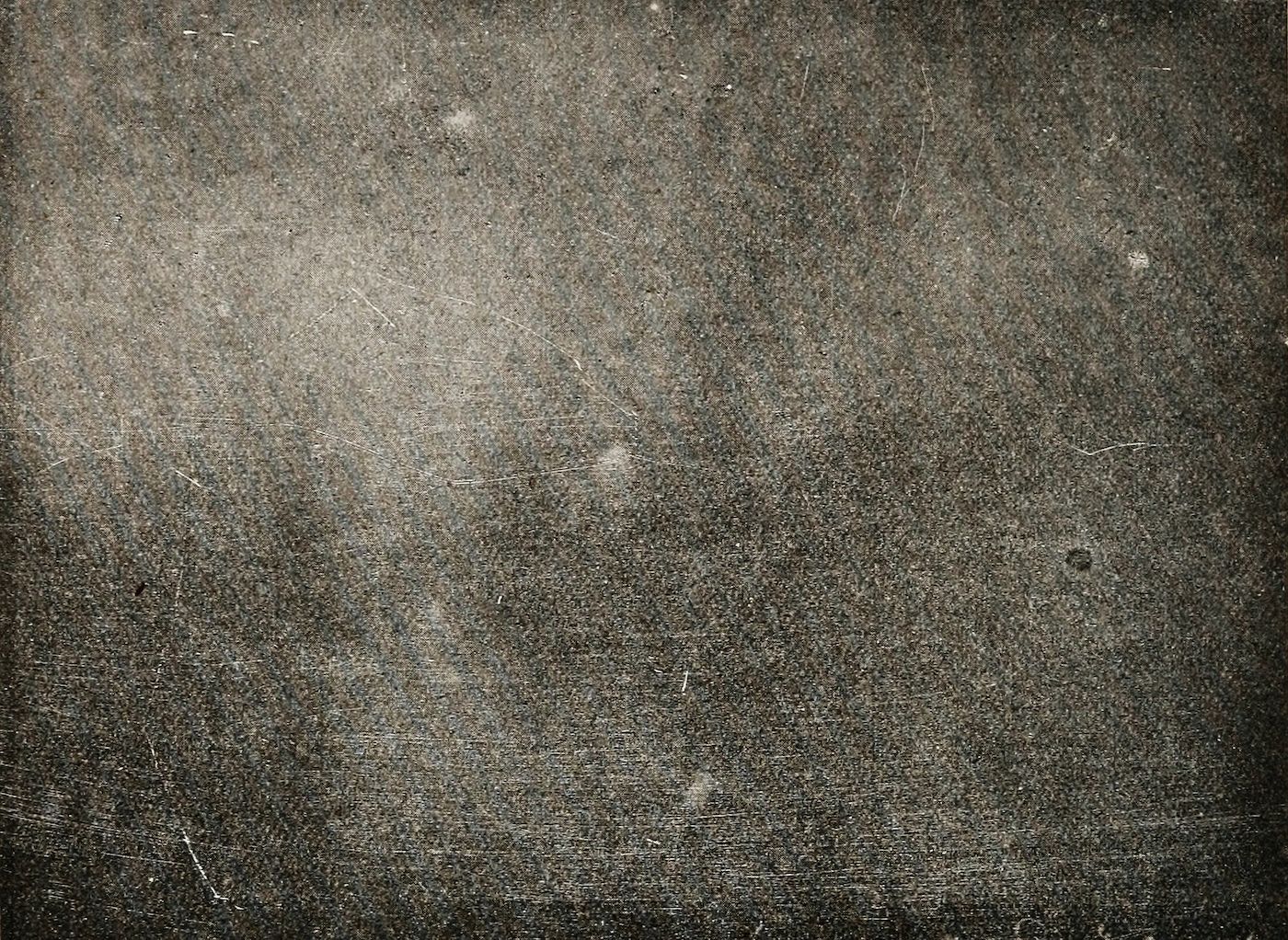 Close-up of a heavily textured, vintage-looking surface with a network of scratches and grain.