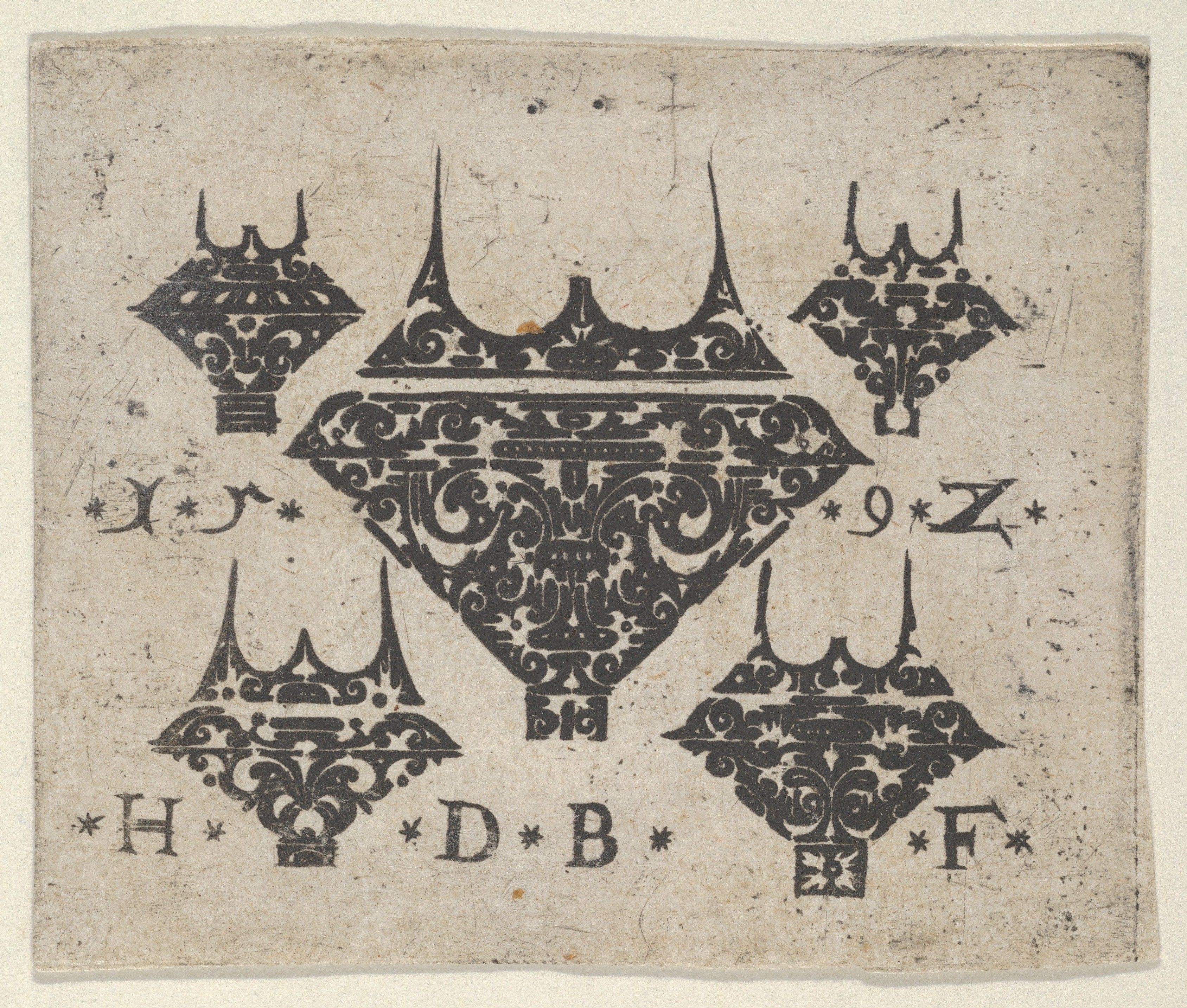A vintage black ink design featuring a central ornate shield-like shape surrounded by four smaller, pointed shapes with letters and star symbols. The design is symmetrical and rendered on a textured, off-white background.