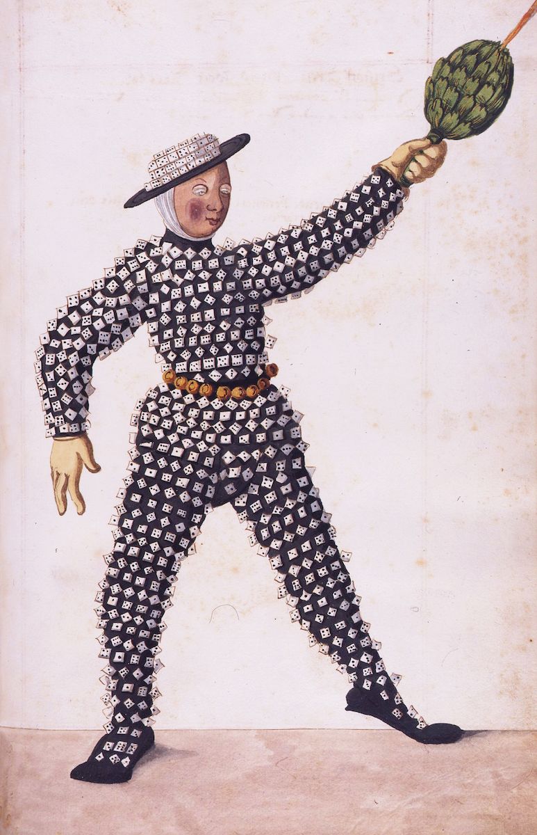 A full-body portrait of a man in a whimsical costume covered in dice, juggling a green ball on a pole.