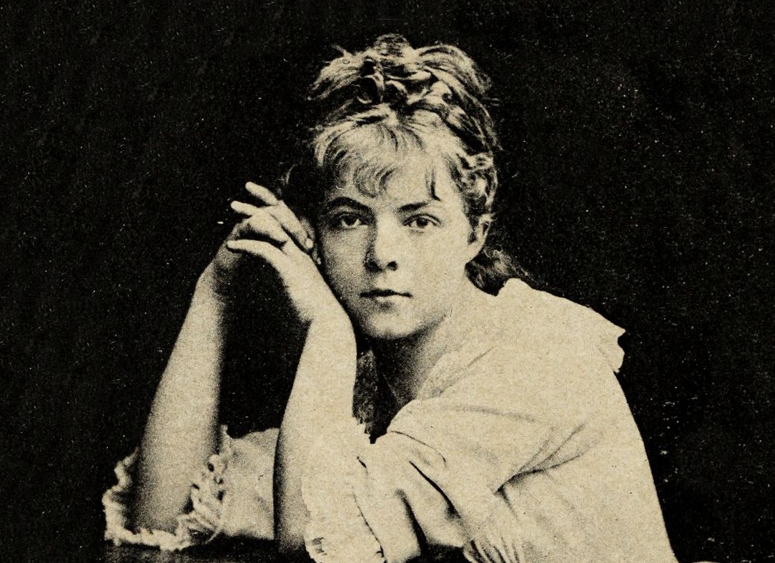 Vintage sepia-toned portrait of a young woman with curly hair and a ruffled dress.