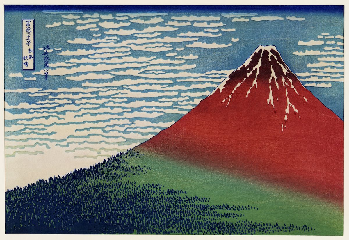 A woodblock print of Mount Fuji with a field and forest in the foreground and a swirling cloud pattern in the sky.