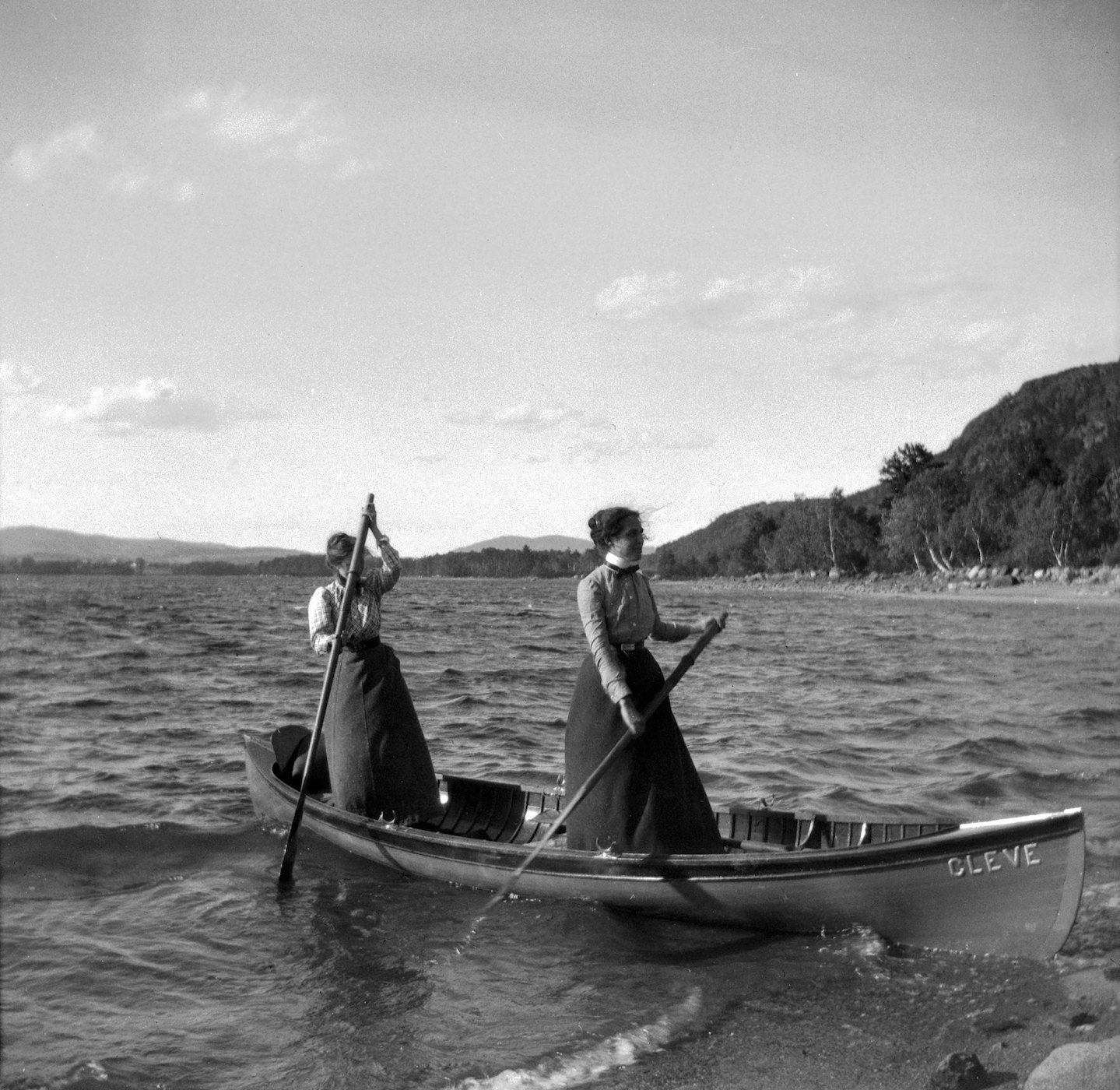 Two women in a canoe on a lake, vintage black and white photograph.