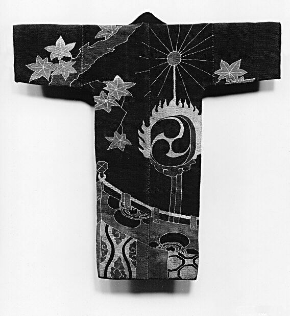 A black kimono with white embroidered designs of maple leaves, a swirling tomoe symbol with flames, a dragon, and a tower.