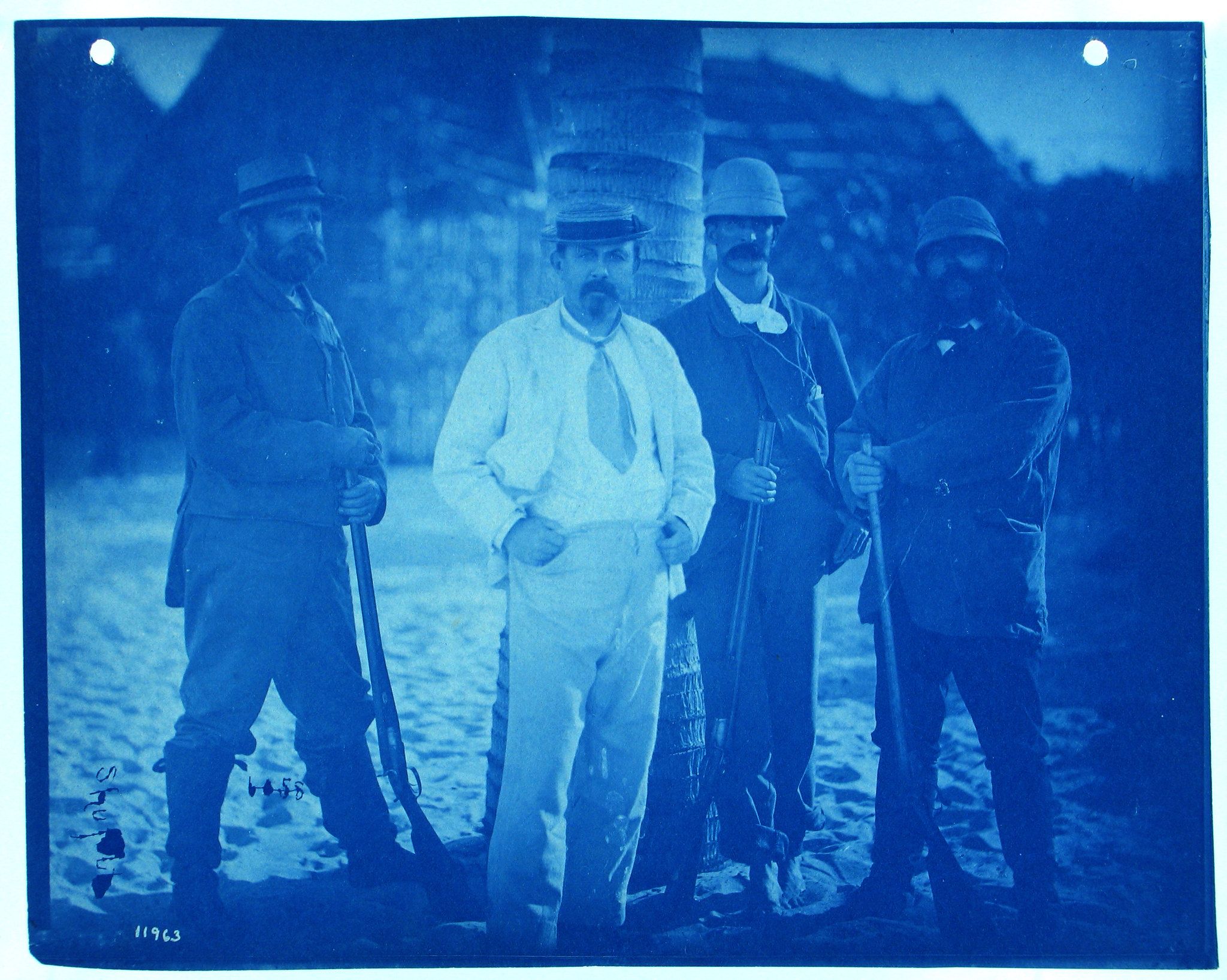 Cyanotype photograph of four men in military uniforms standing in front of a mountainous landscape.