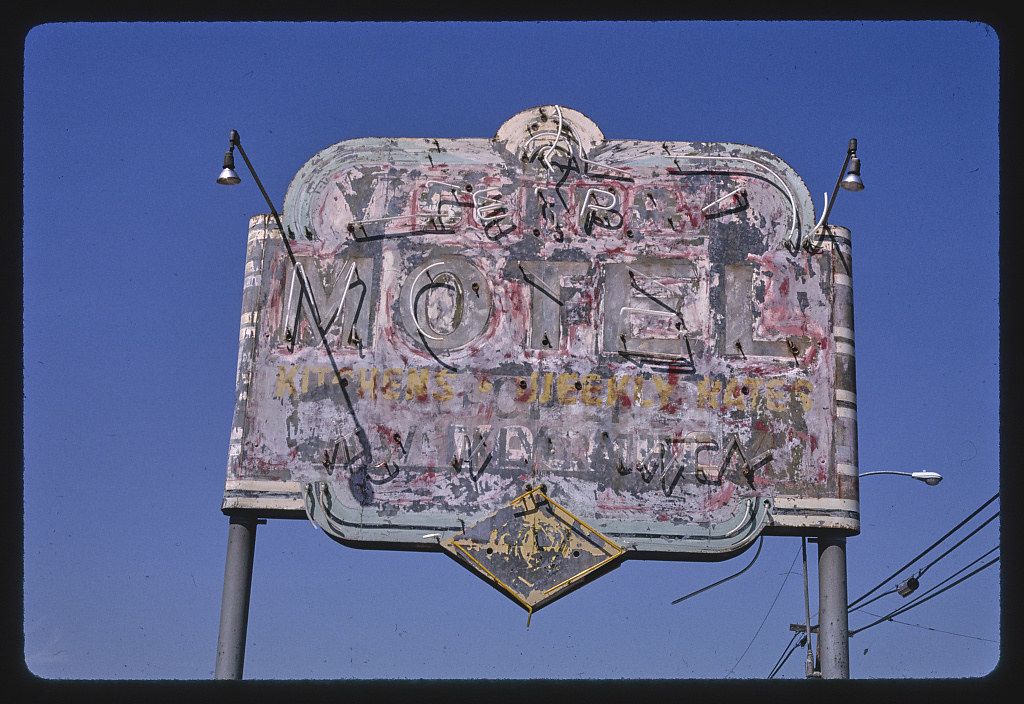 A weathered and dilapidated motel sign against a clear, deep blue sky.