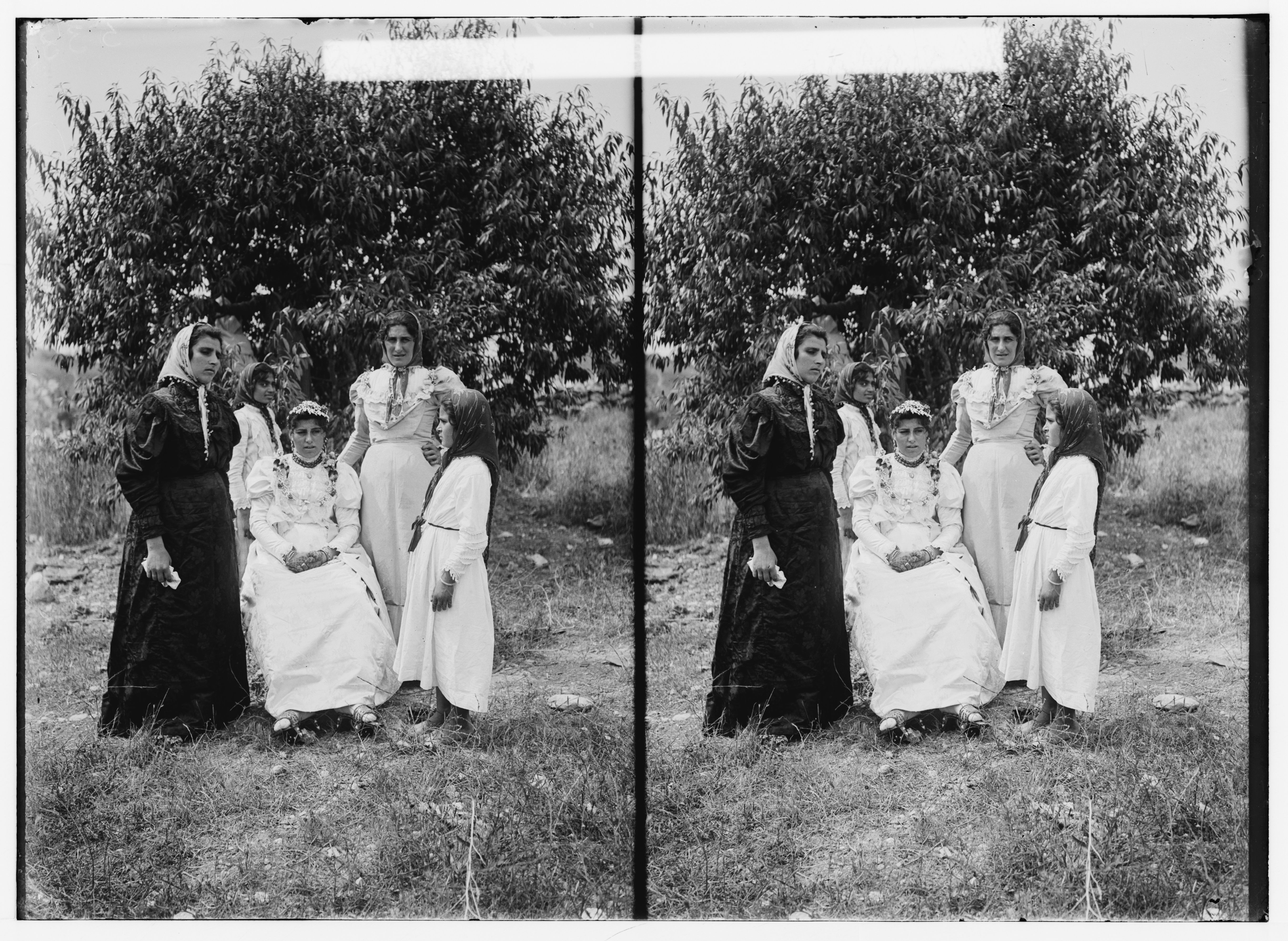 Stereoscopic photograph of five women in white dresses and head coverings standing in front of a tree.