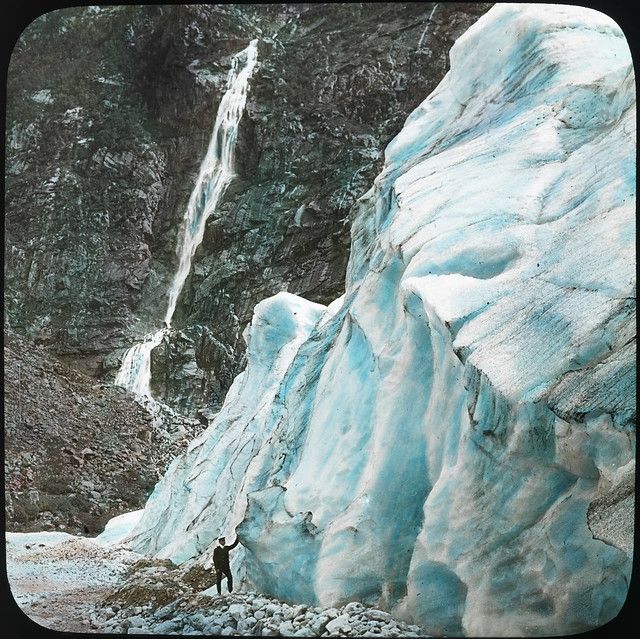 Vintage photograph of a glacier and waterfall with a person standing at the base.