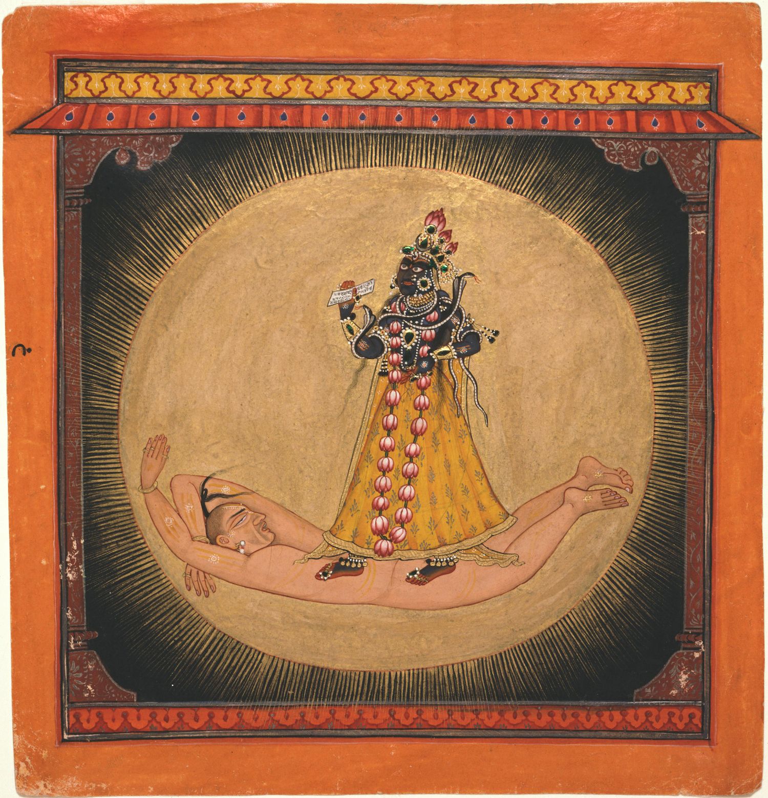 A painting of a dark-skinned deity standing over a reclining figure, adorned with elaborate jewelry and a vibrant yellow robe, set against a dark background with a golden halo and framed by a decorative border.