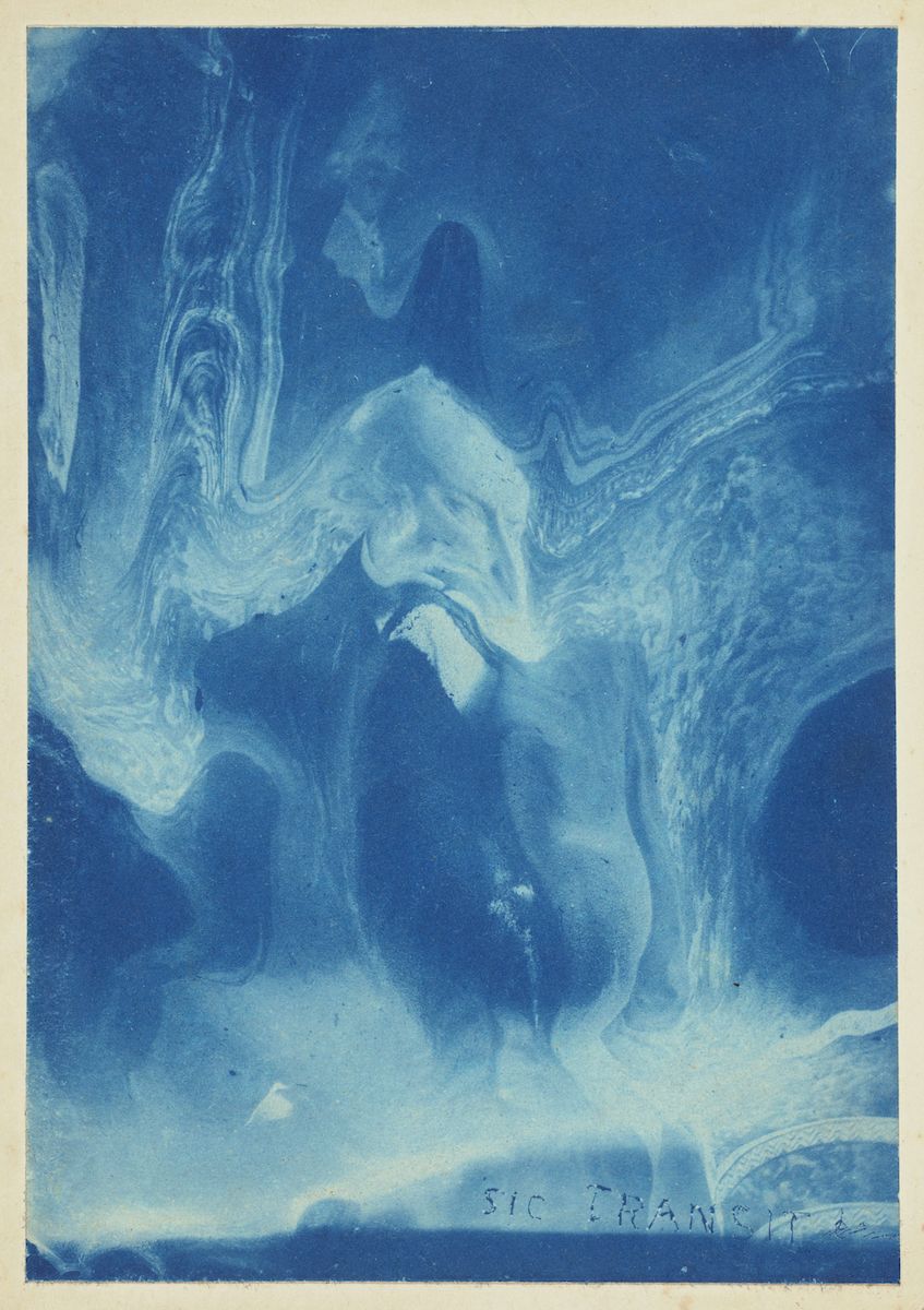 A cyanotype photograph featuring a ghostly human figure amidst swirling blue and white patterns, with the inscription 'SIC TRANSIT' at the bottom.