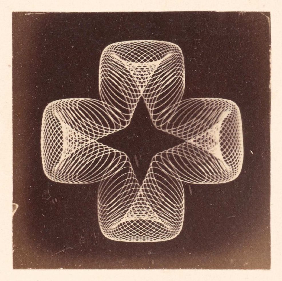 A black and white photograph of a swirling, geometric pattern resembling a four-leaf clover or plus sign, created by a long-exposure light source.