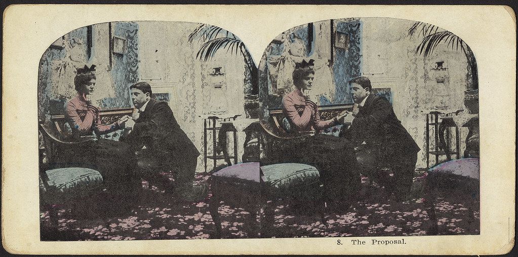Stereoscopic card titled "The Proposal" showing a man and woman in a parlor, with the man appearing to propose to the woman.