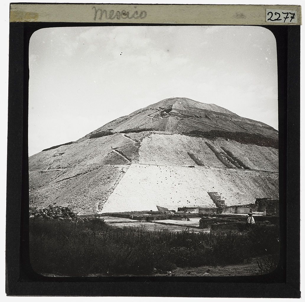 Black and white photograph of a large stepped hill or pyramid-like structure in Mexico, with ruins at its base.