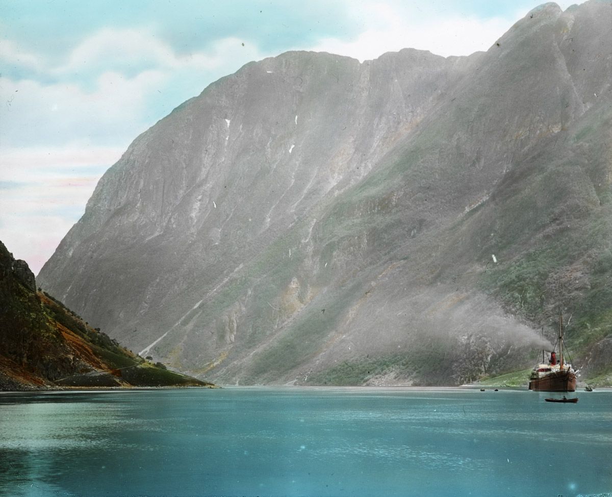 Vintage photograph of a fjord with towering cliffs and a ship.