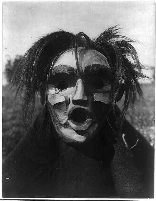 A black and white photograph of a person with a striking, painted face.