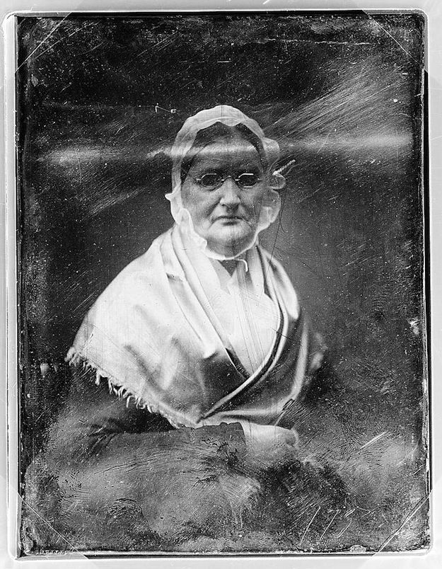 A vintage daguerreotype portrait of an elderly woman wearing a bonnet and spectacles.