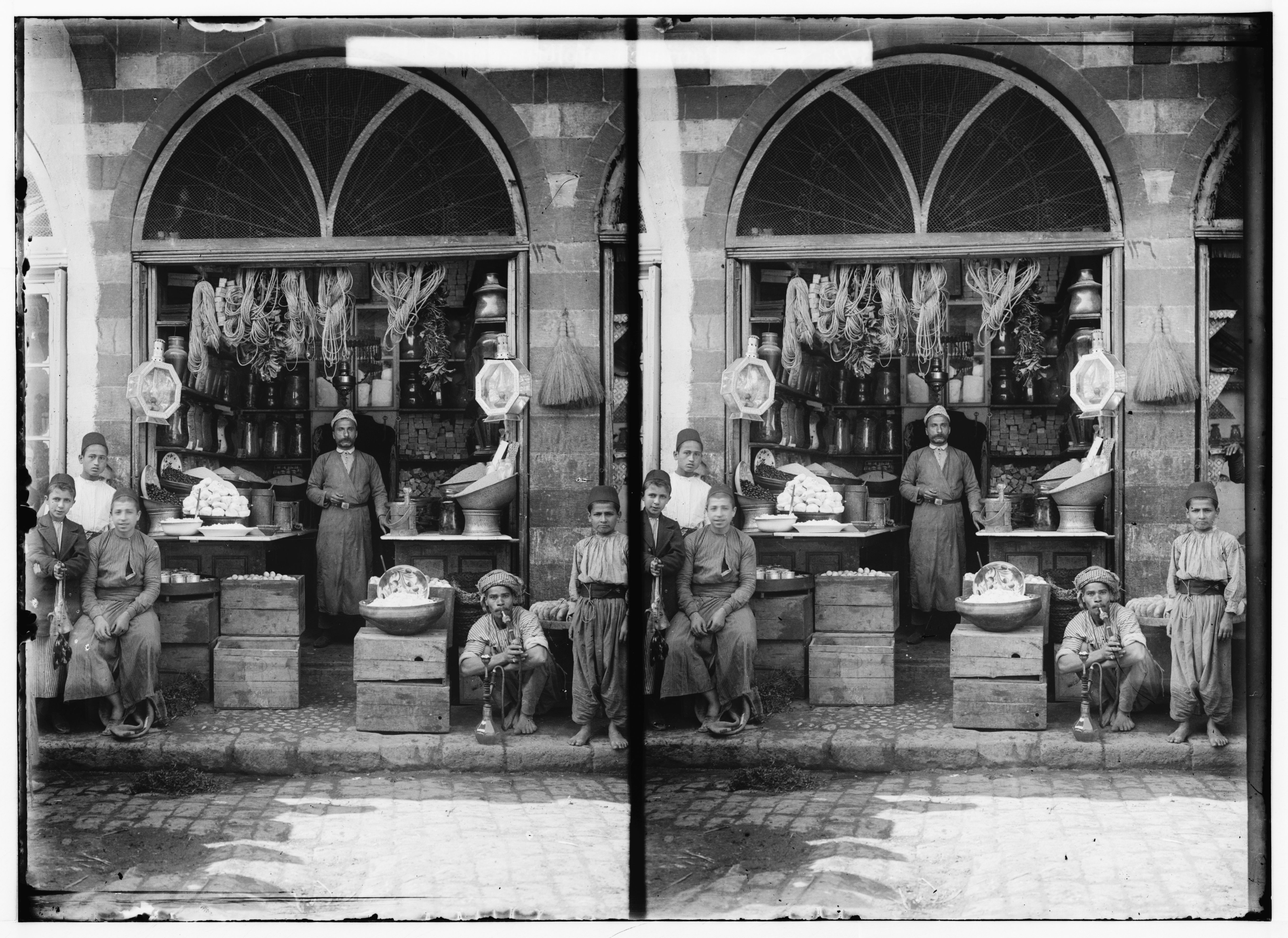 Stereoscopic photograph of a shop with several people posing in front of it.