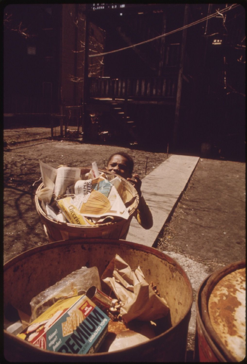 A black and white photograph of a child in a trash can.