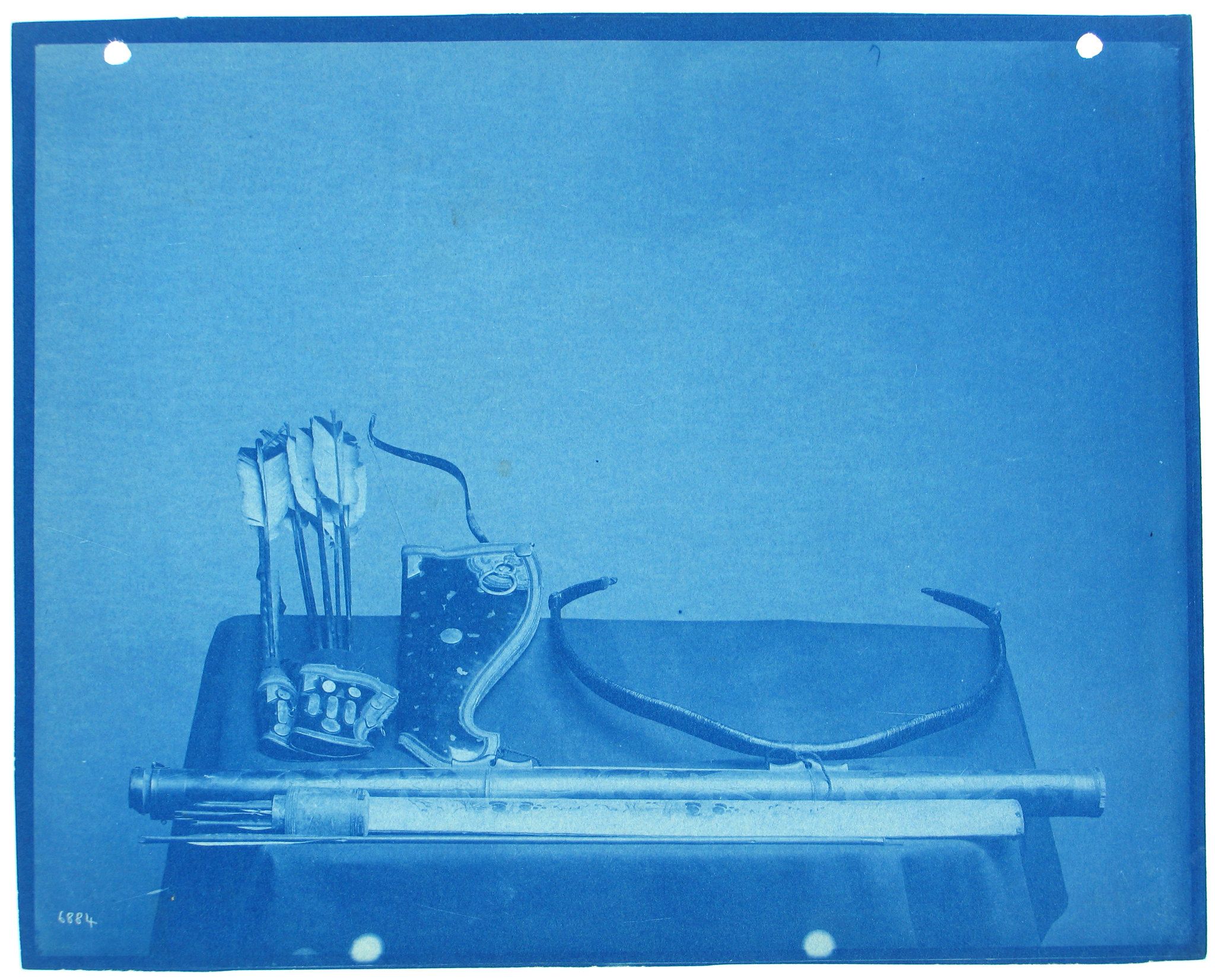 Cyanotype photograph of archery equipment including a quiver of arrows and a bow resting on a stand.