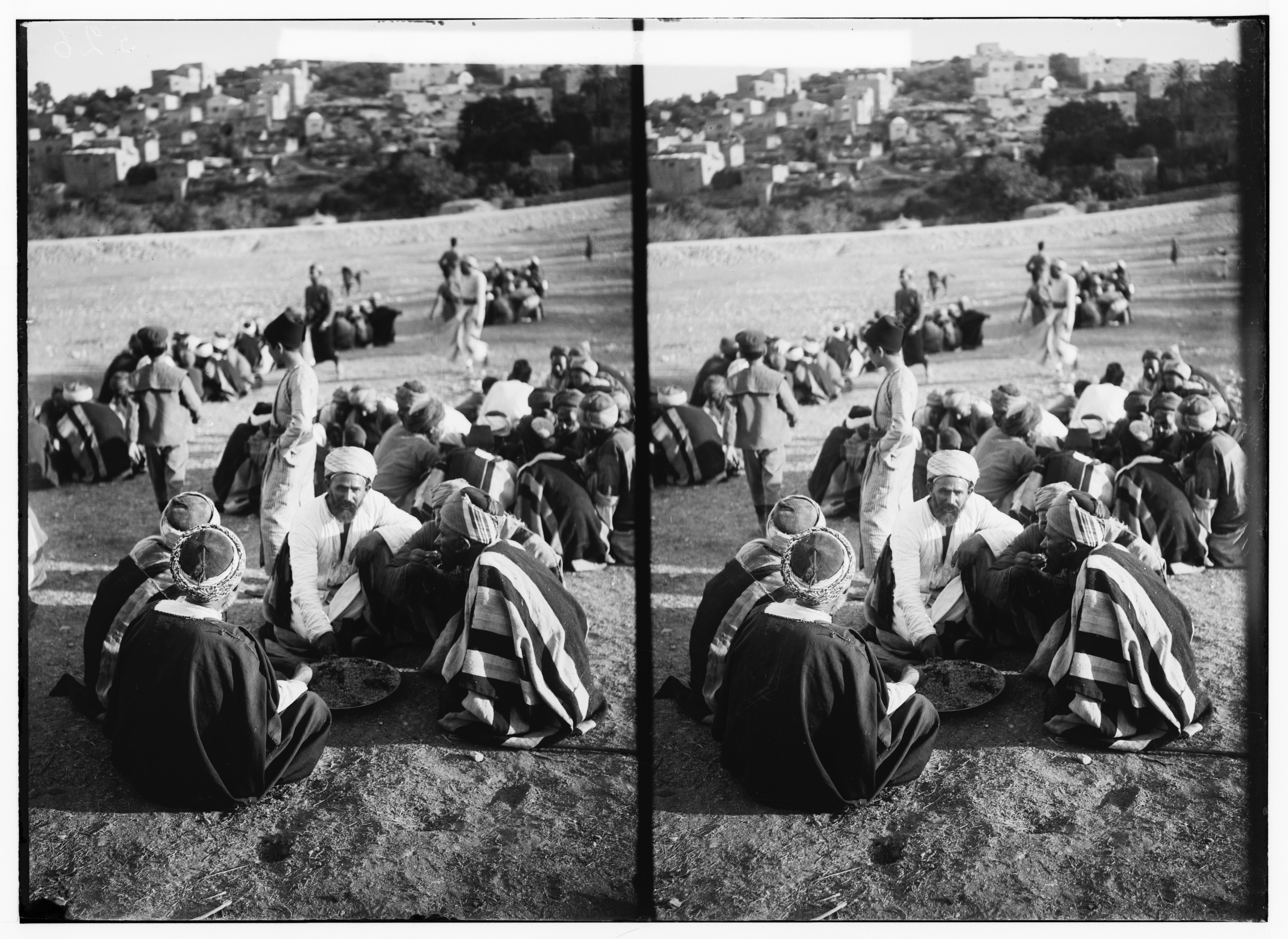 Stereoscopic photograph of a large group of people gathered in a field, with a city visible in the background.