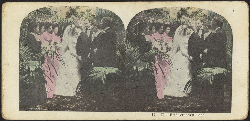 Stereoscope card titled "19. The Bridegroom's Kiss" depicting a wedding scene with a bride and groom surrounded by guests.
