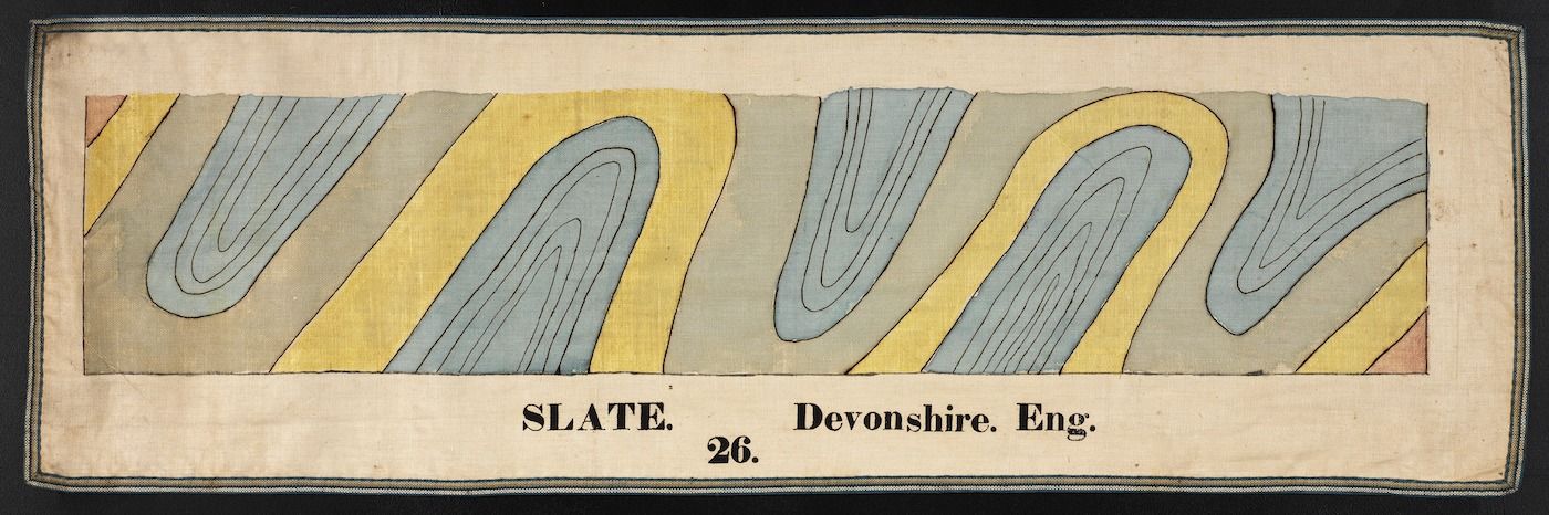 A close-up illustration of slate with swirling patterns in shades of blue, gray, and yellow, labeled "SLATE. Devonshire. Eng. 26."