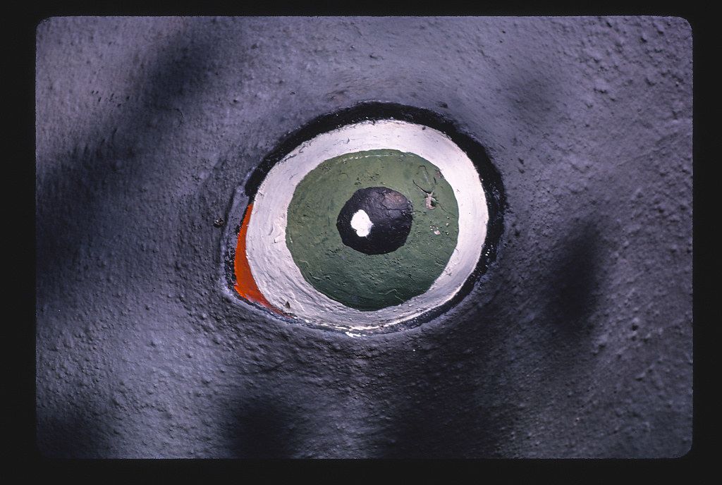 Close-up of a painted eye with concentric rings of color on a textured surface.