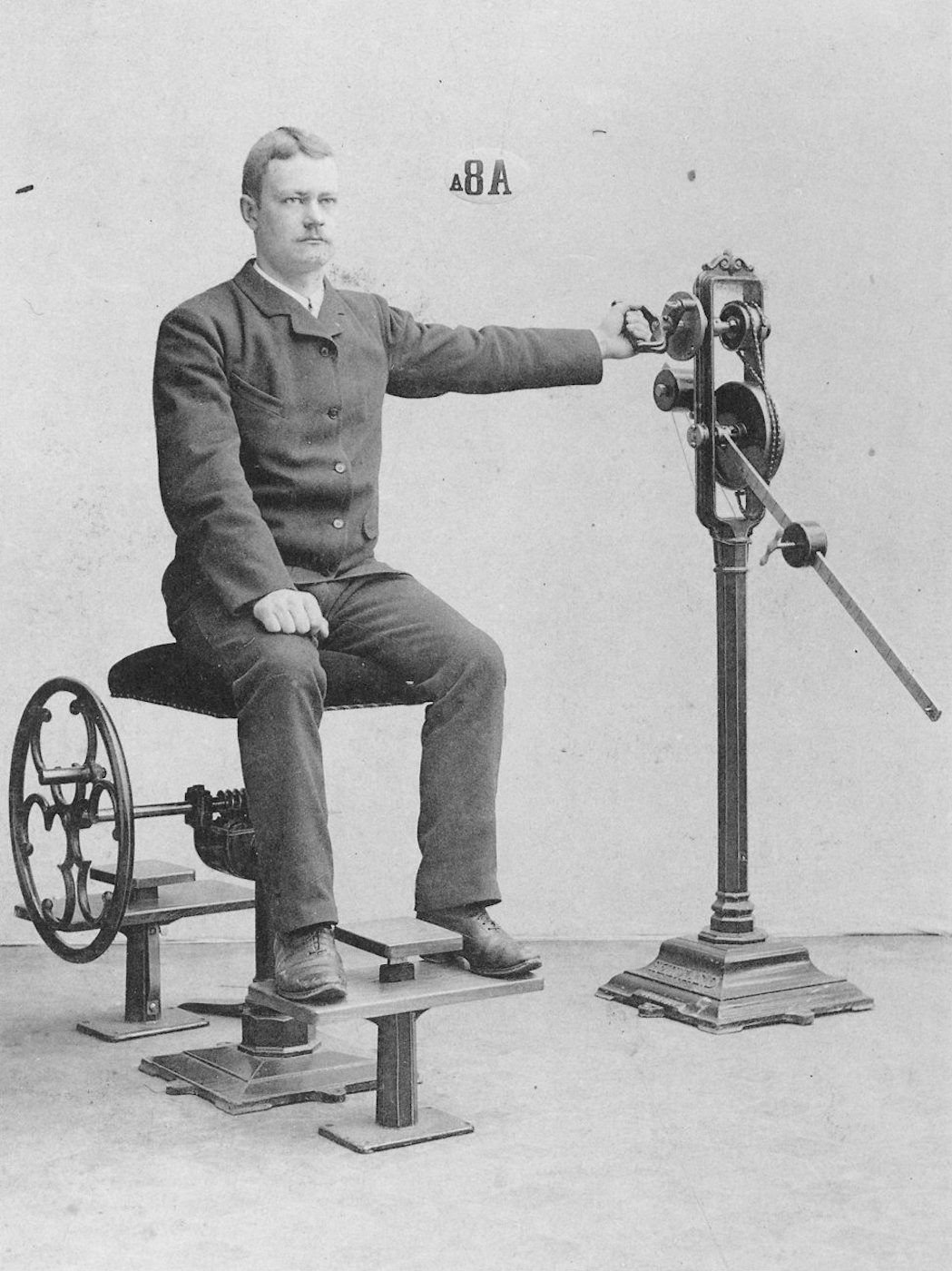 A vintage black and white photograph of a man operating a complex mechanical device.