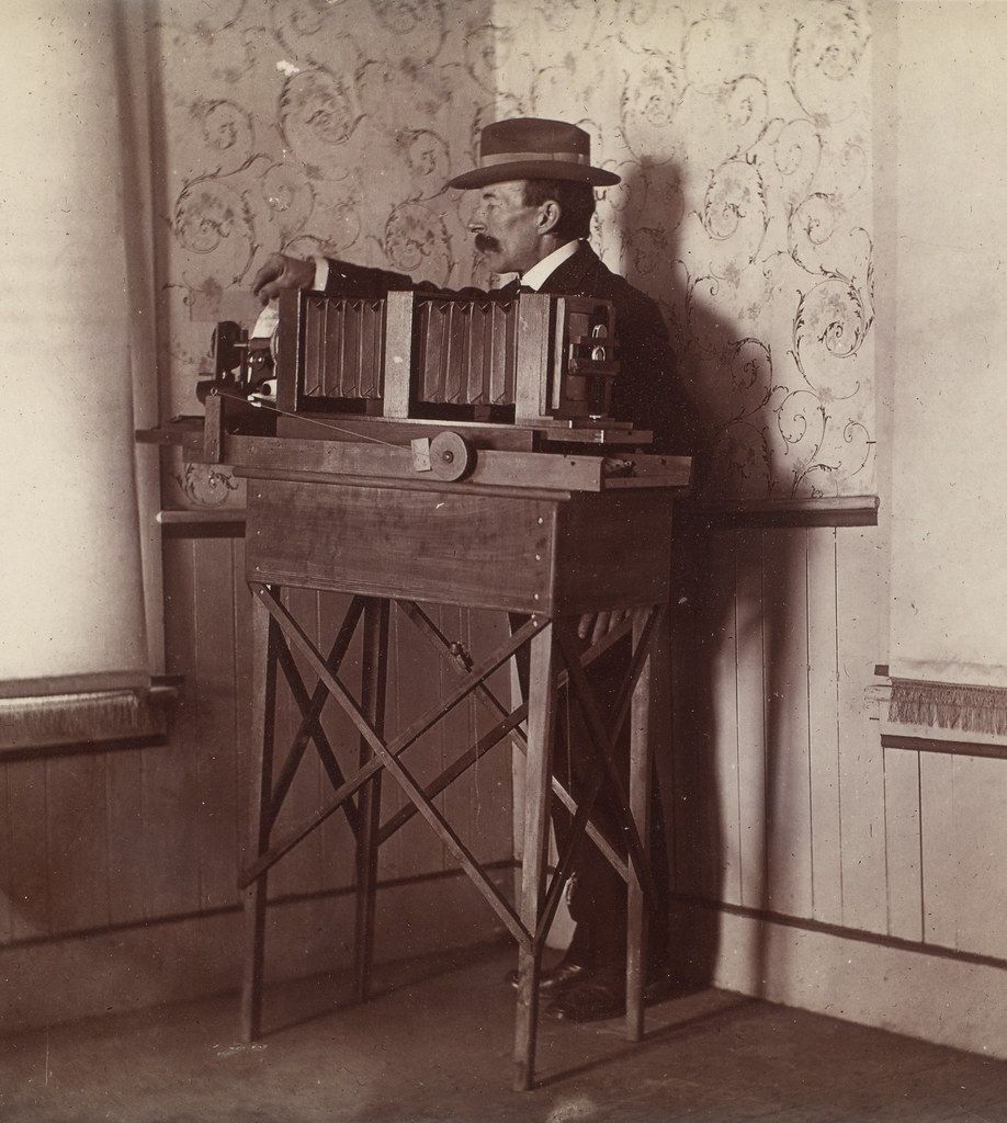 A vintage black and white photograph of a man operating a complex mechanical device.