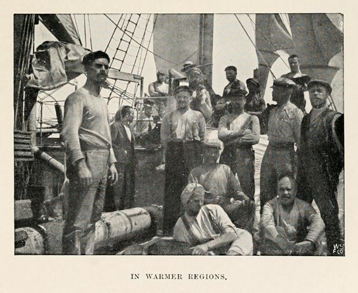 A vintage black and white photograph titled 'In Warmer Regions' depicting a large group of sailors on the deck of a ship.