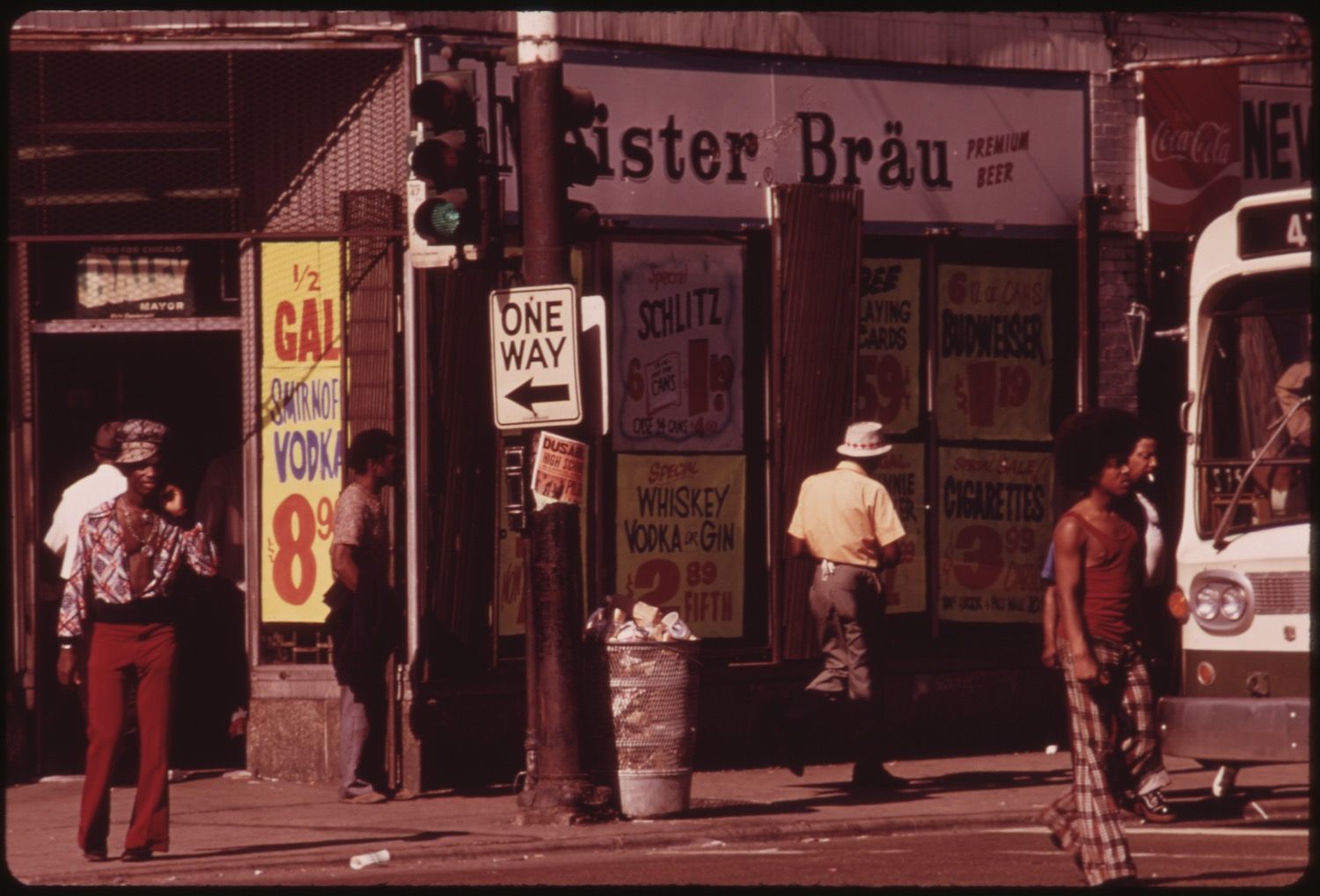 A vintage street scene with a storefront, signs, and three men.