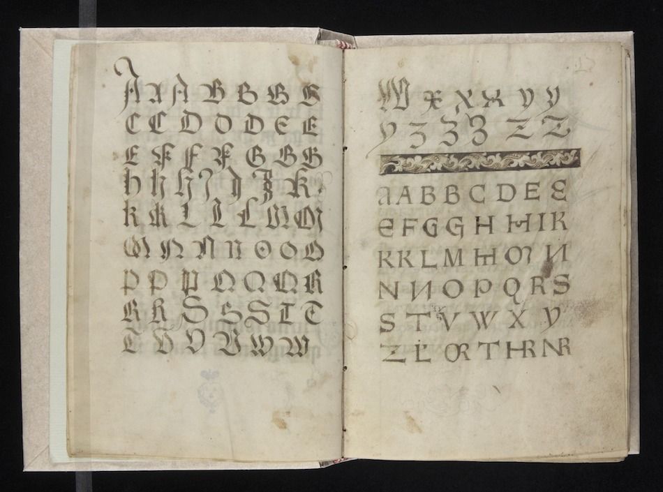 Open book with two pages displaying alphabets in calligraphic script.