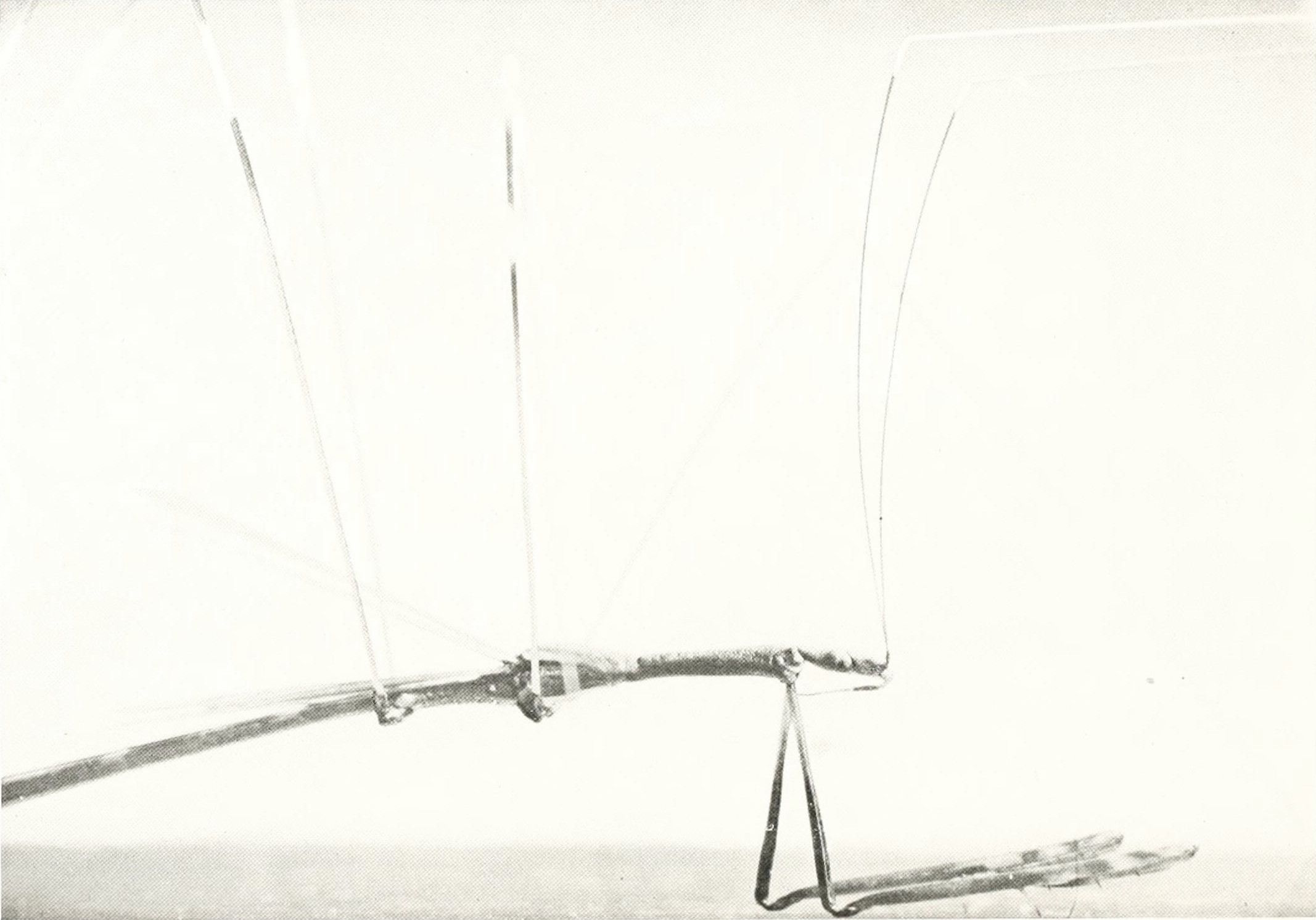 A black and white photograph of a complex antenna structure against a bright sky.