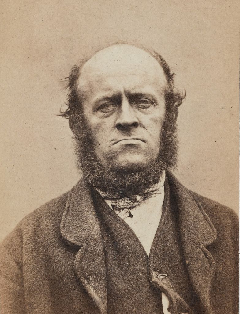 Vintage sepia-toned portrait of a man with a beard and coat.