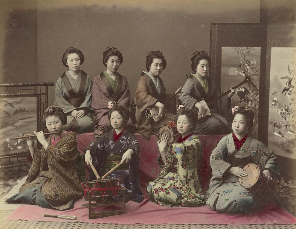 Vintage photograph of eight Japanese women in kimonos playing musical instruments in a traditional room.