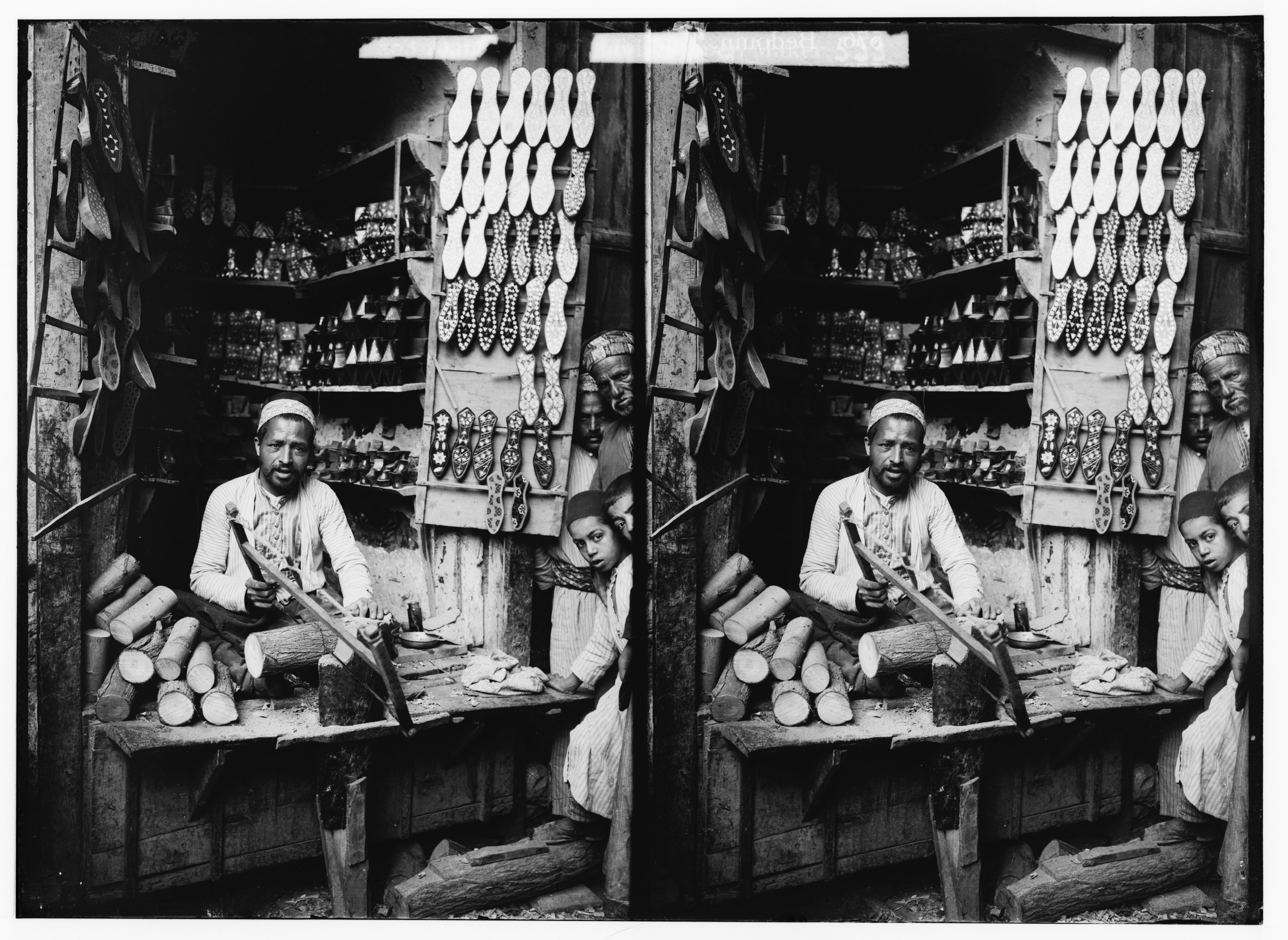 Stereoscopic photograph of a man working in a shop with a young boy standing beside him.