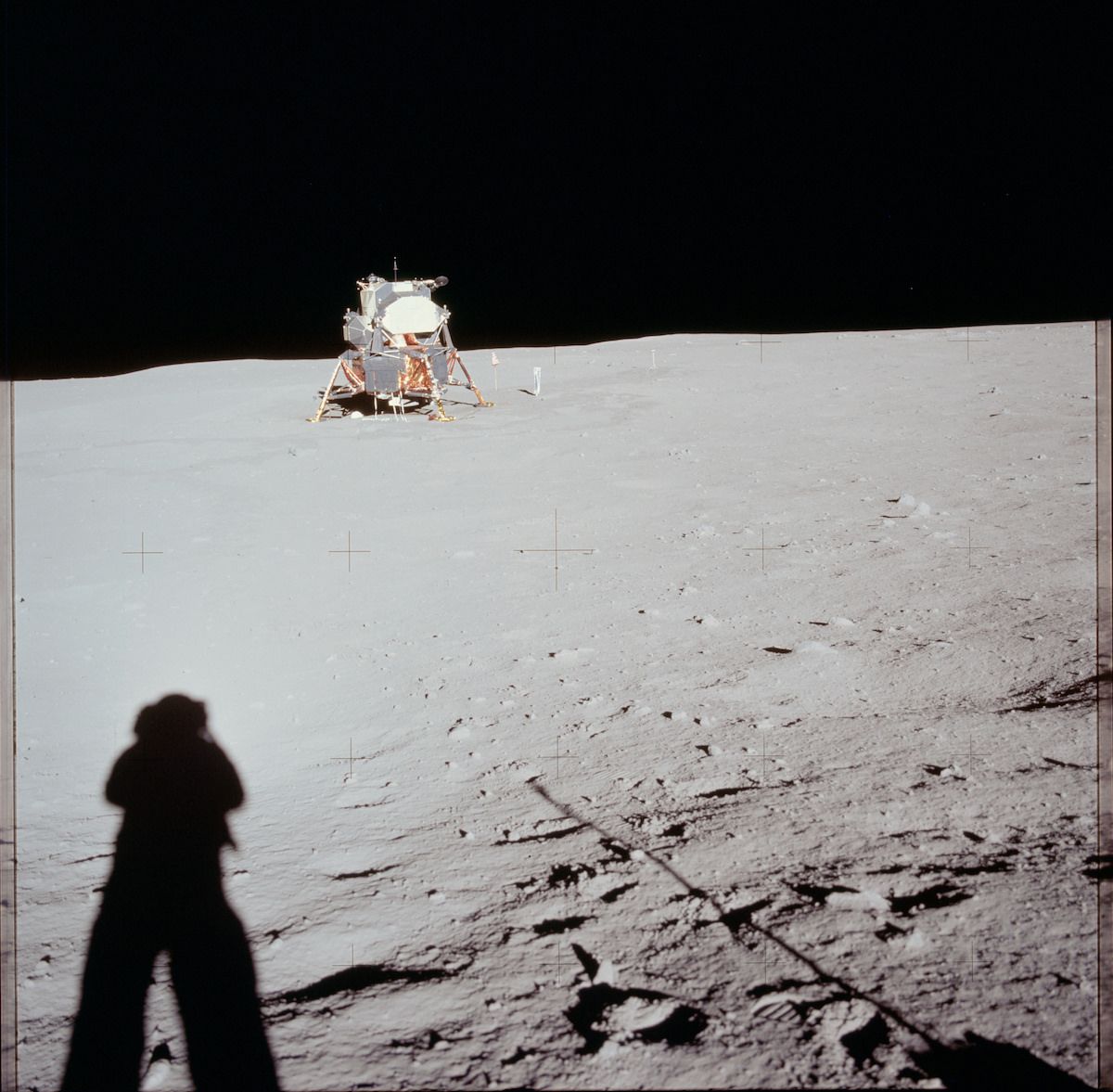 A historic photograph of the lunar module on the moon, with an astronaut taking a picture in the foreground.